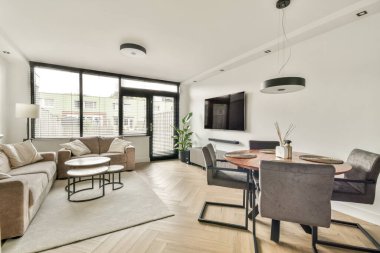 Şık, modern bir oturma odası rahat bir kanepe, zarif bir yemek salonu ve geniş pencerelerden yayılan parlak doğal bir ışık..