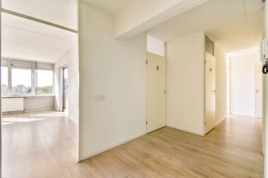 Geniş pencereli, parlak ahşap döşemeli ve minimalist dekorlu parlak ve ferah bir modern koridor. Tasarım basitlik ve işlevselliği vurgular.