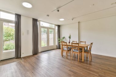 Geniş bir yemek odası, ahşap mobilyalar, geniş pencereler, doğal ışık ve minimalist estetik. Aile toplantıları ve özel yemekler için ideal..