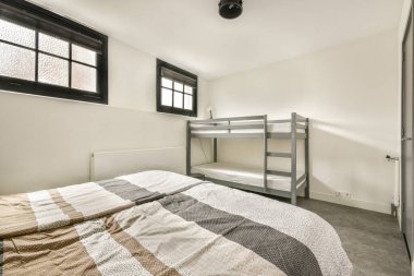 Çift kişilik ranza ve büyük pencerelerden süzülen doğal ışık filtreli şık gri dekorlu modern bir minimalist yatak odası..