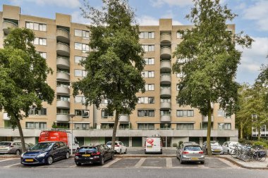Çağdaş bir apartman ön planda park etmiş arabalarla ve yemyeşil çimenliklerle betimlenerek canlı bir mahallede yaşayan şehirlileri gözler önüne seriliyor..