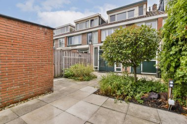 Çeşit çeşit bitki, ağaç ve modern doğa tasarımı içeren iyi korunmuş bir bahçesi olan sakin bir bahçe..