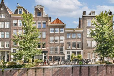 Zarif kanal evleri, Amsterdam 'ın zengin kültürel mirasını yansıtan yemyeşil ağaçlar ve bisikletlerle çevrili eşsiz bir mimariye sahip..