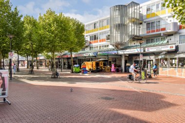 Değişik mağaza vitrinleri ve yayaların yeşil ağaçlar ve modern mimari arasında günün tadını çıkardığı canlı bir şehir alışveriş alanı..