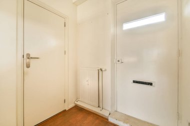 Beyaz duvarları, ahşap zemini ve basit kapı tasarımları olan temiz ve minimalist bir giriş. Uzay modern ve davetkar bir atmosfer yayar..