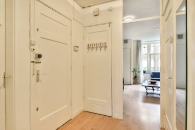 Beyaz duvarları, ahşap döşemeleri ve davetkar bir atmosferi olan modern bir koridor. Açık düzen konforlu bir yaşam alanına götürür.