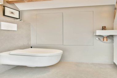 Beyaz bir tuvalet, nötr tonlar ve minimalist dekorun yer aldığı gösterişli ve çağdaş bir banyo. Modern iç tasarım ve ilham için idealdir..