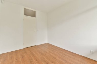 Düz beyaz duvarları ve ahşap zemini olan boş bir minimalist oda, iç tasarımda basitlik sergiliyor..
