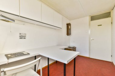 Beyaz bir masa, basit bir sandalye ve düz duvarlar içeren temiz ve minimalist bir çalışma alanı. Organizasyonu desteklemek ve profesyonel bir ortama odaklanmak için ideal.