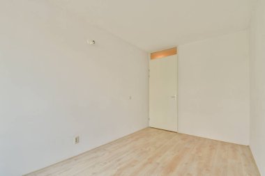 Geniş, minimalist bir iç mekan. İçinde çıplak duvarlar ve ahşap döşemeler var. Çeşitli kullanım alanları için sakin ve davetkar bir atmosfer yaratıyor..