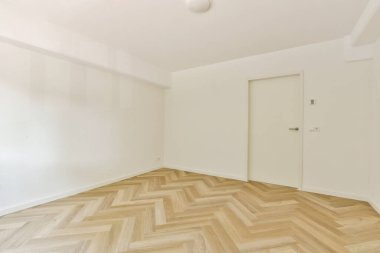 Ringa kemiği ahşap zeminli ve düz duvarlı, parlak ve havadar bir atmosfer sağlayan modern minimalist bir tasarımı sergileyen boş bir oda..