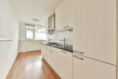 Beyaz dolap, temiz tezgah ve çağdaş bir yaşam alanı için minimalist tasarım unsurlarının yer aldığı gösterişli ve modern bir mutfak..