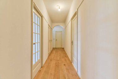 Beyaz duvarları ve ahşap döşemeleri olan parlak koridor, modern iç mekanlar için sakin ve davetkar bir atmosfer yaratıyor..