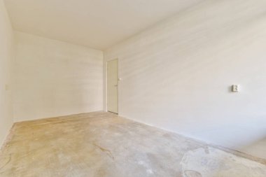 Çıplak bir duvar ve doğal ışıklandırma içeren boş, minimalist bir iç mekan, çeşitli kullanımlar için açık ve havadar bir atmosfer yaratıyor..