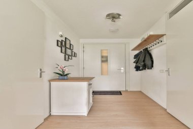 Paltosu, dekoratif masası ve parlak giriş kapısı olan şık bir girişi olan temiz ve minimalist bir koridor..