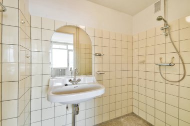 Beyaz fayanslardan oluşan gösterişli ve minimalist bir banyo modern musluğu olan basit bir lavabo ve oval bir ayna. Uzay, temiz ve ferahlatıcı bir ortam sunar..