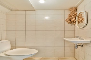 Duvar monte edilmiş lavabosu ve zarif dekoruyla gösterişli, modern bir banyo. Tarafsız fayanslar sakin atmosferi güçlendirir..