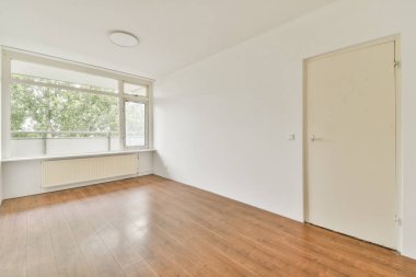 Geniş pencereli, ahşap döşeme ve minimalist tasarım ile tamamlanmış doğal ışığın mekanı aydınlatmasına izin veren bir hava odası..