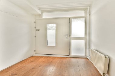 Tarafsız duvarların olduğu parlak ve temiz bir giriş salonu, doğal ahşap döşeme, ve büyük cam bir kapı, hoş bir ortam yaratıyor..