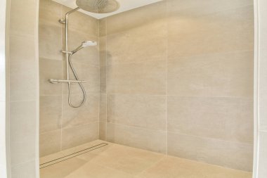 Pürüzsüz bej döşemeleri ve minimalist bir tasarımı olan gösterişli, modern bir duş. Çağdaş tuvaletler için mükemmel. Temiz ve zarif görünmeyi hedefliyor..