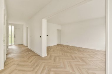 Geniş, modern bir iç mekan, parlak ahşap döşeme ve beyaz duvarlar, çağdaş yaşam alanları için ideal minimalist bir tasarımı vurguluyor..