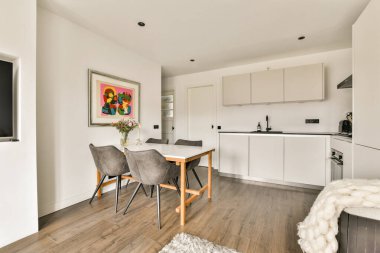 Minimalist tasarım elementleri, gösterişli dolaplar ve sanatsal dekorları olan rahat bir yemek alanı içeren şık ve modern bir mutfak..