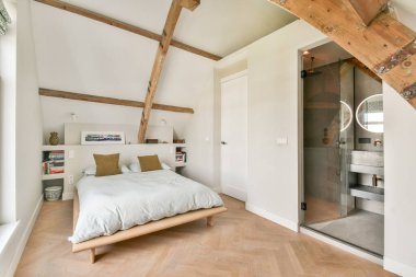 Huzurlu, modern bir yatak odası, ahşap kirişler, minimalist bir tasarım, ve rahat bir yatak, rahatlatıcı bir renk paletinde konfor ve stil karışımı sergiliyor..