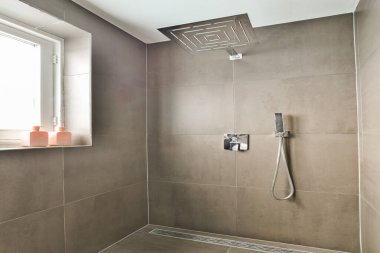 Zarif fayanslar, çağdaş bir duş başlığı ve şık bir görünüm için minimalist tasarım unsurları içeren gösterişli ve modern bir banyo banyosu..