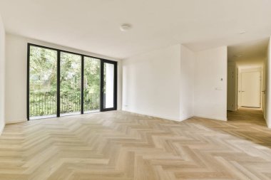 Zarif ringa kemiği döşemesi ve basit bir renk paleti ile doğal ışığı davet eden geniş pencereli, modern bir iç mekan..