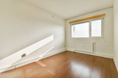 Parke zeminli minimalist bir oda ve pencereden süzülen yumuşak güneş ışığı huzurlu bir atmosfer ve modern estetik yaratıyor..