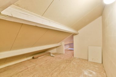 Eğimli tavanları, ahşap kirişleri ve çıplak döşemeleri olan boş bir tavan arası, kişiselleştirmeye hazır, temiz ve minimalist bir tasarım sergiliyor..