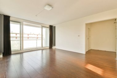 Geniş, boş, modern bir oda. Geniş pencereler, doğal ışık ve cilalanmış ahşap döşeme. İç dizayn için ideal..