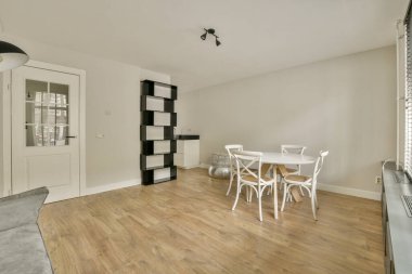 Minimalist mobilyaların, gösterişli bir yemek masasının ve açık renkli bir paletin bulunduğu geniş, aydınlık bir oda yaşamak için sakin bir atmosfer yaratıyor..