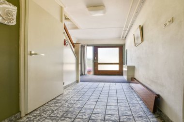 Modern dekor ve doğal ışığın karışımından oluşan, davetkar bir atmosfer yaratan iyi tasarlanmış bir koridor. Döşeme ve kapı karakter ekler.