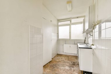 Beyaz kiremitli duvarları, doğal ışık penceresi ve fonksiyonel aletleri olan çağdaş bir mutfak vitrini..