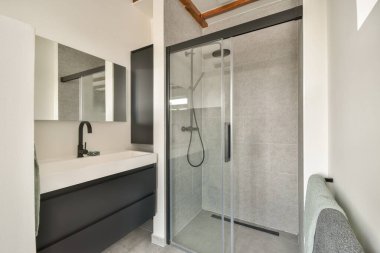 Zarif ve çağdaş bir banyo. Parlak bir duş muhafazası, modern eşyalar ve temiz bir estetik için nötr bir ton..