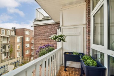 Çok güzel düzenlenmiş bir balkon, canlı bitki saksılarını modern mimarinin arka planına karşı sergiliyor. Bahçe meraklıları için ideal.