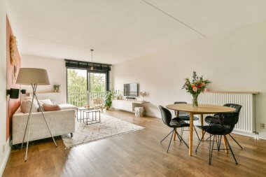 Minimalist mobilyaların, doğal ışığın ve sıcak bir atmosferin olduğu şık bir oturma odası. Rahatlama ve sosyal toplantılar için ideal..
