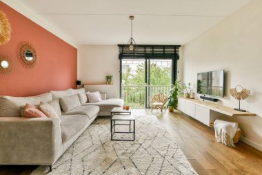 Tarafsız bir kanepe, dekoratif elementler, geniş pencereler ve modern tasarımın yeşillikle harmanlandığı şık ve rahat bir oturma odası..