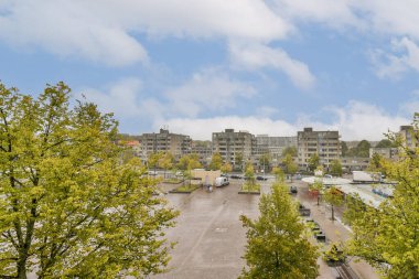 Çağdaş binaların, park alanlarının ve yemyeşil çimlerin yer aldığı modern şehir manzarası, şehir ortamında doğanın karışımını gösteriyor..