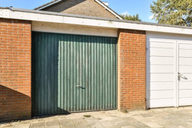 Belirgin yeşil kapısı ve katı beyaz duvarı olan çağdaş bir tuğla bina. Tasarım, şehir mimarisini doğanın dokunuşuyla harmanlıyor..