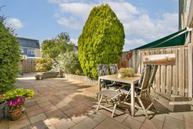 Etrafı yeşilliklerle çevrili, sakin bir ortamda rahatlamak ya da toplanmak için mükemmel bir açık hava oturma alanı içeren parlak bir veranda..