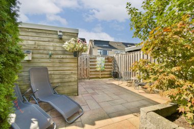 Tahta paneller, şezlonglar ve yemyeşil yemyeşil, dinlenmek ve güneşli havanın tadını çıkarmak için mükemmel bir avlu..