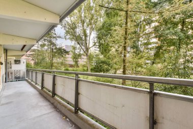 Çağdaş bir balkon, yemyeşil manzaralı, rahatlama ve açık hava keyfi için tasarlanmış. Kentsel ayarlar için ideal.
