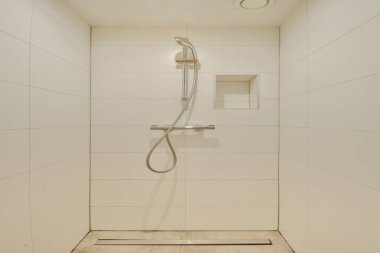 Bu resim, temiz çizgileri, modern bir duş başlığı ve çağdaş banyo estetiğini gösteren basit bir fayans işi olan gösterişli, minimalist duş tasarımını içeriyor..