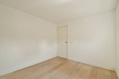 Düz beyaz duvarlar ve ahşap döşemeler içeren ferah ve minimalist bir iç mekan, çeşitli kullanımlar için ideal sakin bir atmosfer yaratıyor..