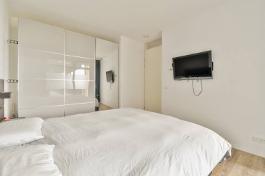 Geniş ve parlak modern bir yatak odası. Düzgün döşenmiş bir yatak odası ve duvara monte edilmiş bir televizyonu var. Rahatlamak ve rahatlamak için mükemmel..