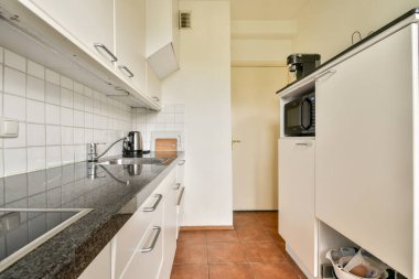 Zarif, modern bir mutfak, minimalist dolaplar, granit tezgahlar, ve verimli bir yemek alanı oluşturan iyi organize edilmiş bir düzen..