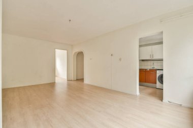 Açık renkli duvarlar ve ahşap döşemeler içeren, çeşitli iç mimari veya dekorasyon fikirleri için ideal minimalist bir tasarım sergileyen boş bir oda..
