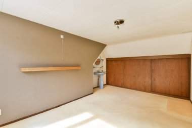 Ahşap bir raf ve nötr renk paleti olan dolapların yer aldığı minimalist bir iç mekan. Oda, çeşitli tasarım fikirleri için ideal basitlik ve zarafet yayar..